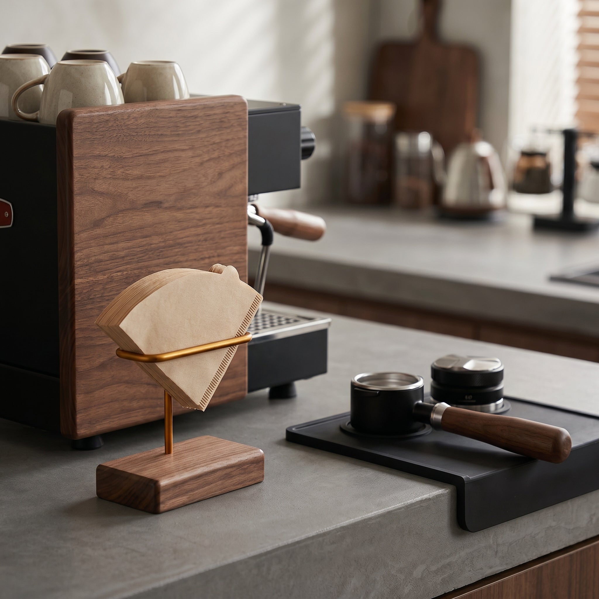 The Gable filter cradle with unbleached brown paper filters positioned on a gray concrete workstation beside a walnut-paneled espresso machine and a commercial portafilter.