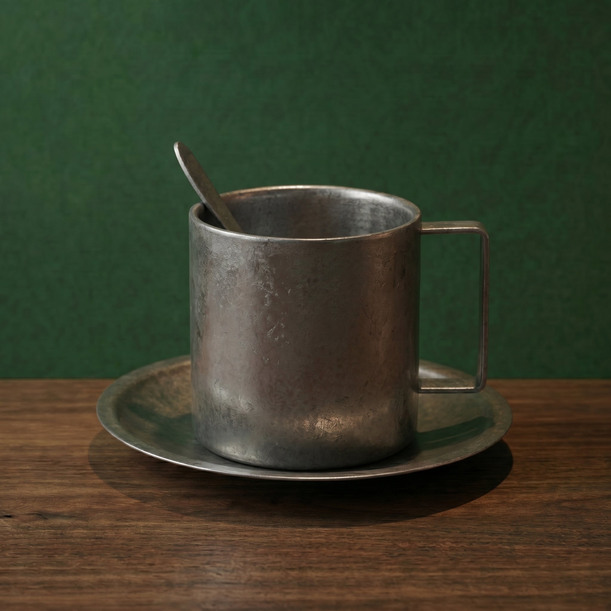 Close-up shot of the tall-cylindrical frosted steel coffee mug with a geometric square handle on a wood surface.