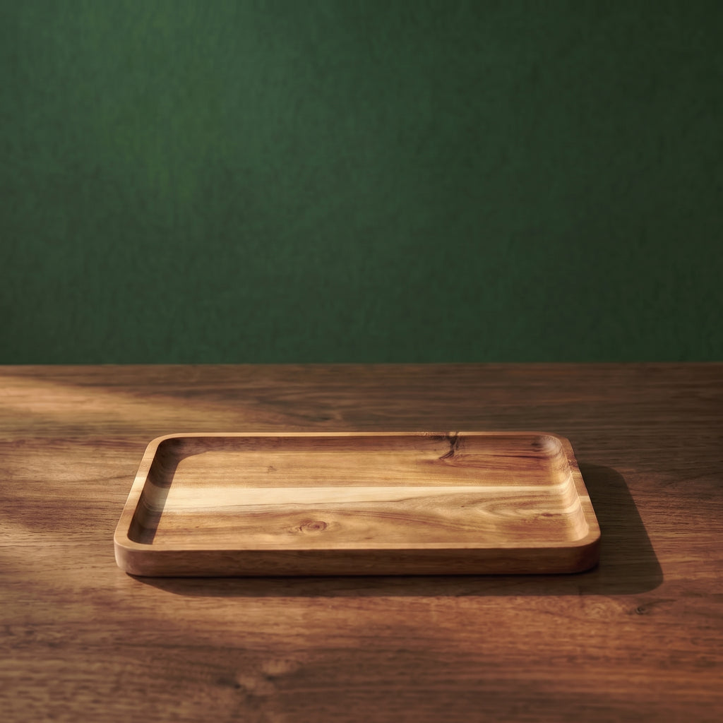 Vance beveled walnut wood serving tray with a wide rectangular profile, shown on a rustic wooden counter against a dark green studio wall.