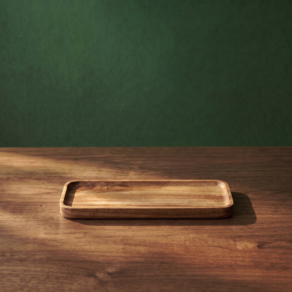 Small Vance beveled walnut wood tray displayed on a wooden tabletop against a textured dark green background, showcasing its slim profile for cafe or restaurant service.