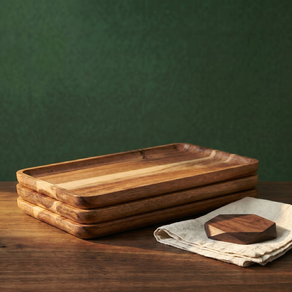 A structural stack of four modular Vance rectangular wood trays resting on a walnut counter next to a linen cloth and a geometric timber coaster.